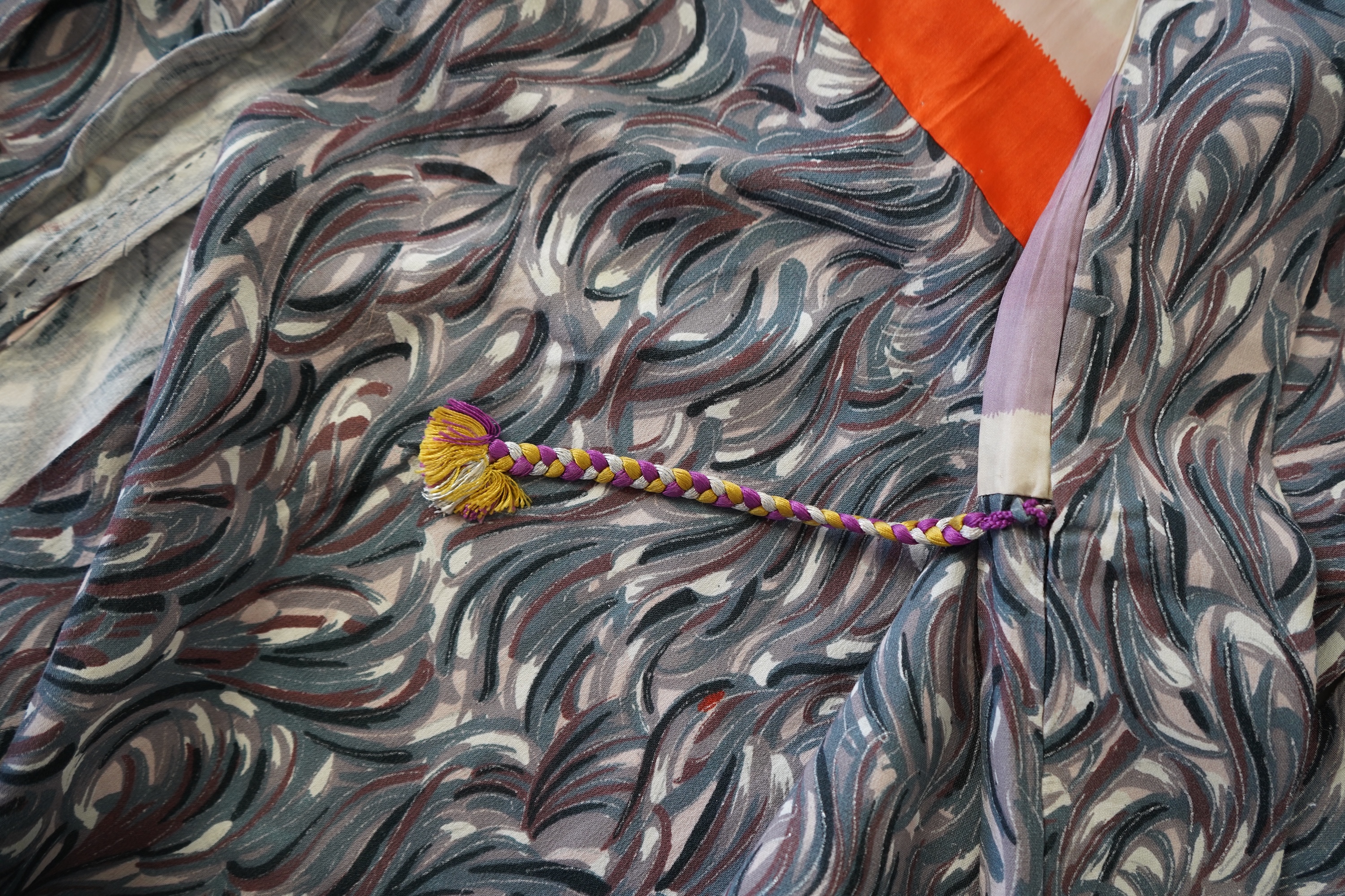 Three Japanese mid 20th century ‘Haori’ printed silk jackets. One red with brightly coloured lining and rust brown floral silk lining. All with large kimono sleeves. Grey patterned Haori, 79cm long., Condition - good